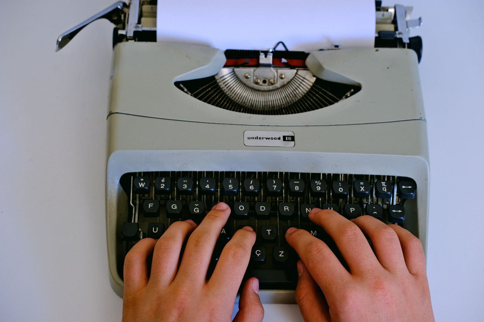 Hands typing on a typewriter, representing the 2021 reporting of Darkness in a Lighthouse
