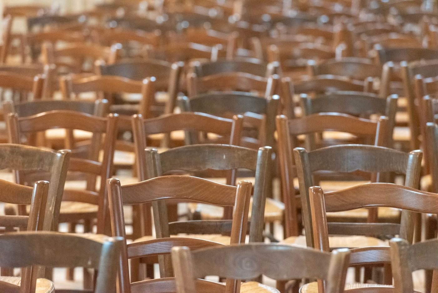 Rows of empty wooden chairs in a church hall