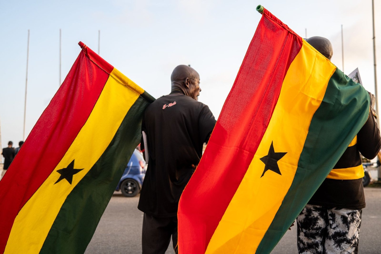 Two men holding Ghanaian flags at a public event in Ghana